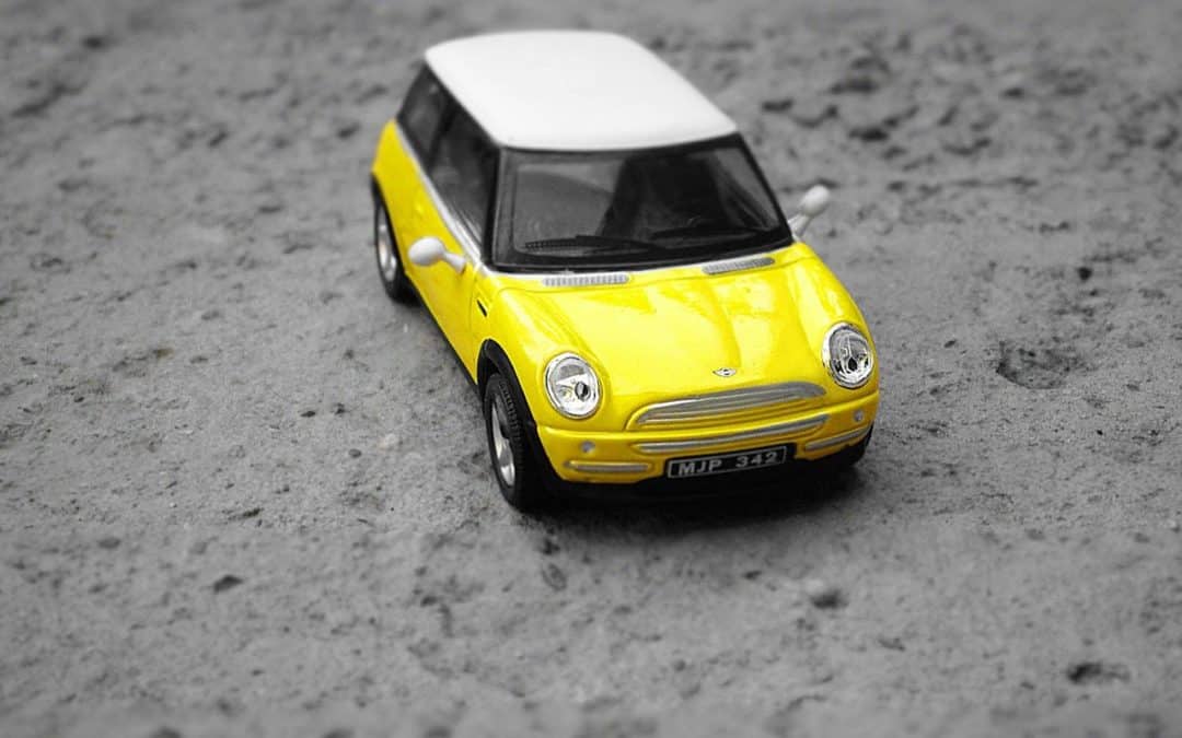A lemon law attorney examines a yellow toy car on the ground.