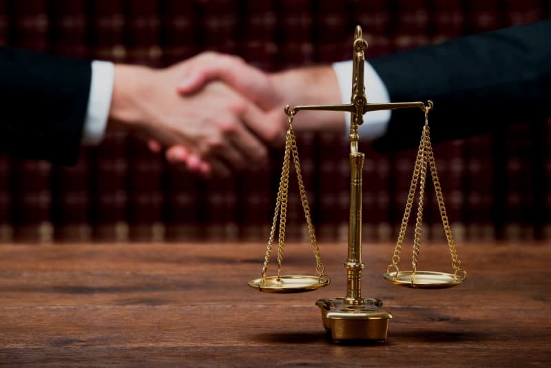 Two San Diego businessmen, including a lawyer, shaking hands over a scale of justice.
