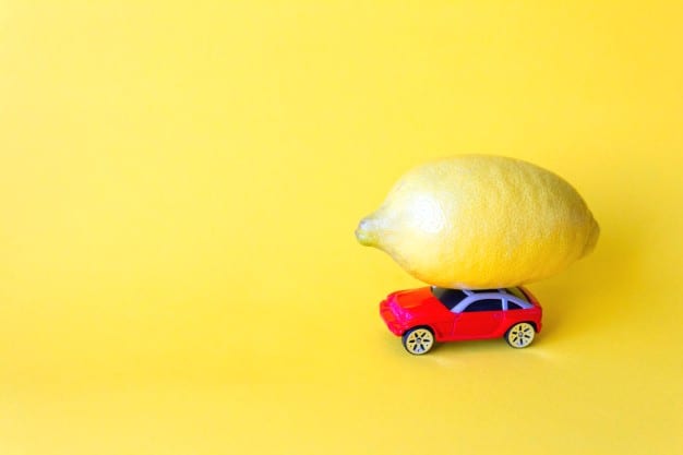 A lemon on top of a toy car.