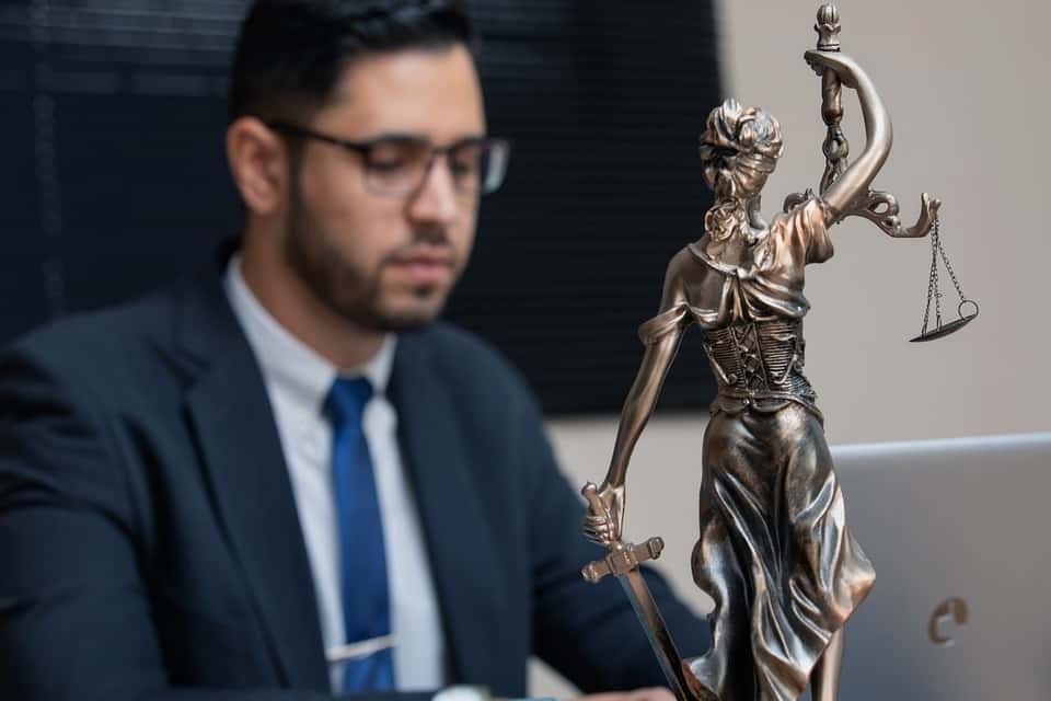 A California attorney in a suit sitting at a desk with a statue of justice.