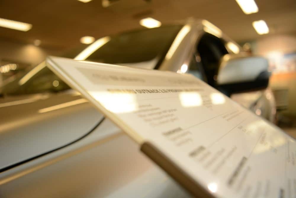 A lemon law attorney in California examines a car with a paper on it parked in a showroom.