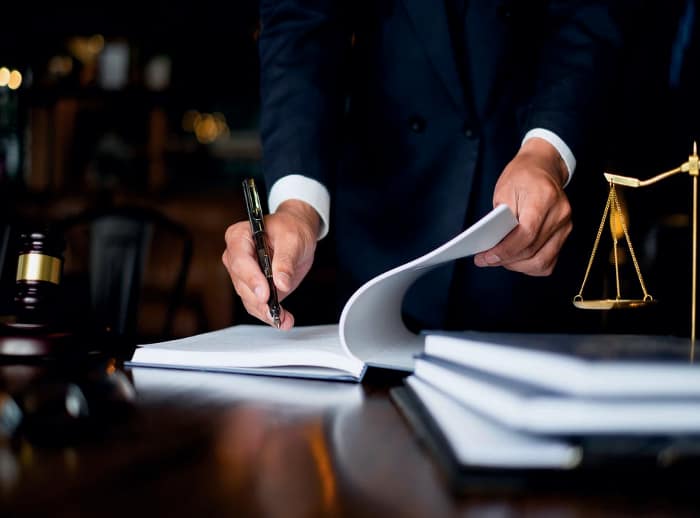 A attorney in a suit is signing a document on a table in San Diego.