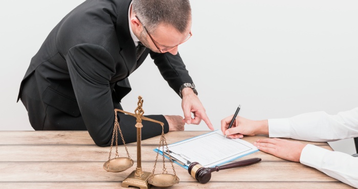 Two attorneys shaking hands in front of a scale.