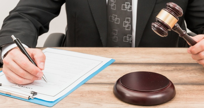 A San Diego attorney using a gavel to settle a lemon law case involving a car on top of money.