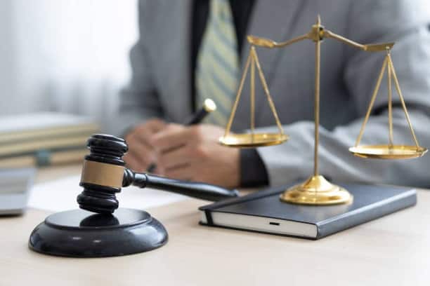 A man in a suit sits at a desk with a judge's gavel explaining California Lemon Law.