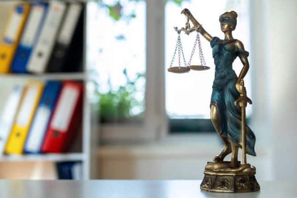 A statue of a lady holding scales on a desk representing California Lemon Law.