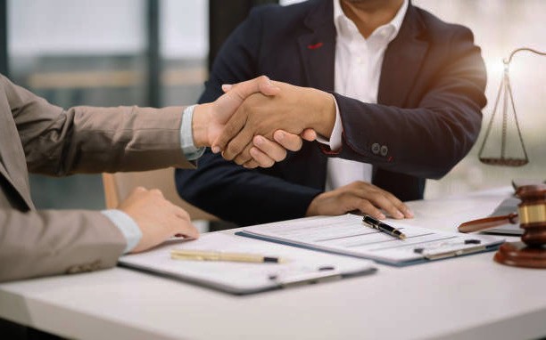 Two businessmen shaking hands at a desk showcasing Lemon Law Expertise.