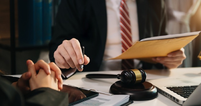 A gavel and scales of justice rest on a wooden table in a dimly lit courtroom, symbolizing law and balance, much like the fairness sought under California lemon law for faulty cars.