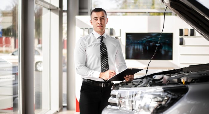 A man stands by the roadside, gazing thoughtfully at the open hood of his car, pondering if his used car could fall under CA lemon law.