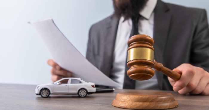 In a grassy area, a woman stands by a white car with the hood open, talking on her cellphone. She might be discussing the California auto lemon law to find out how to resolve her vehicle troubles efficiently.