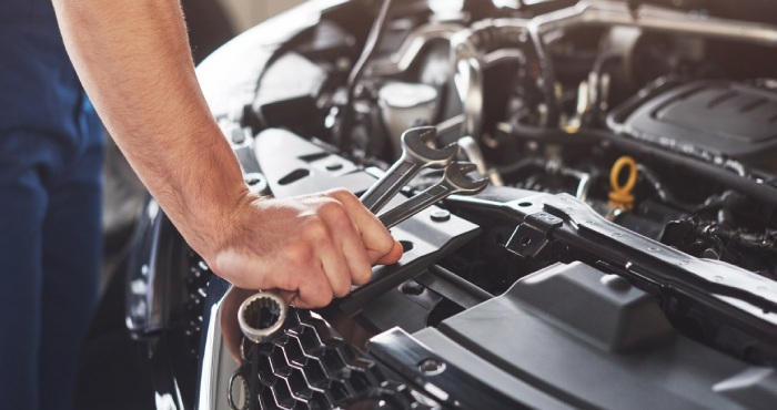 A mechanic's hand, symbolic of courtroom success, holds wrenches while working meticulously on a car engine.