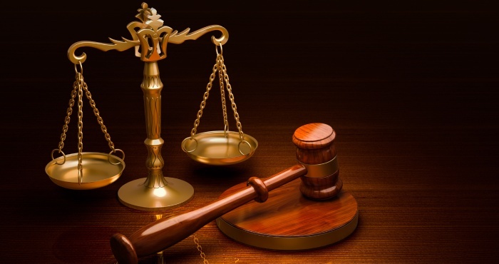 A wooden gavel rests beside a pair of balanced golden scales on a dark surface, echoing the justice served under the California Lemon Law.