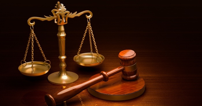 A golden balance scale and a wooden gavel rest on a dark surface, embodying justice and law, reminiscent of the California Lemon Law's protections.