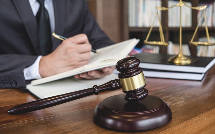 A woman in a suit is writing on a notebook as a lemon law lawyer in California.
